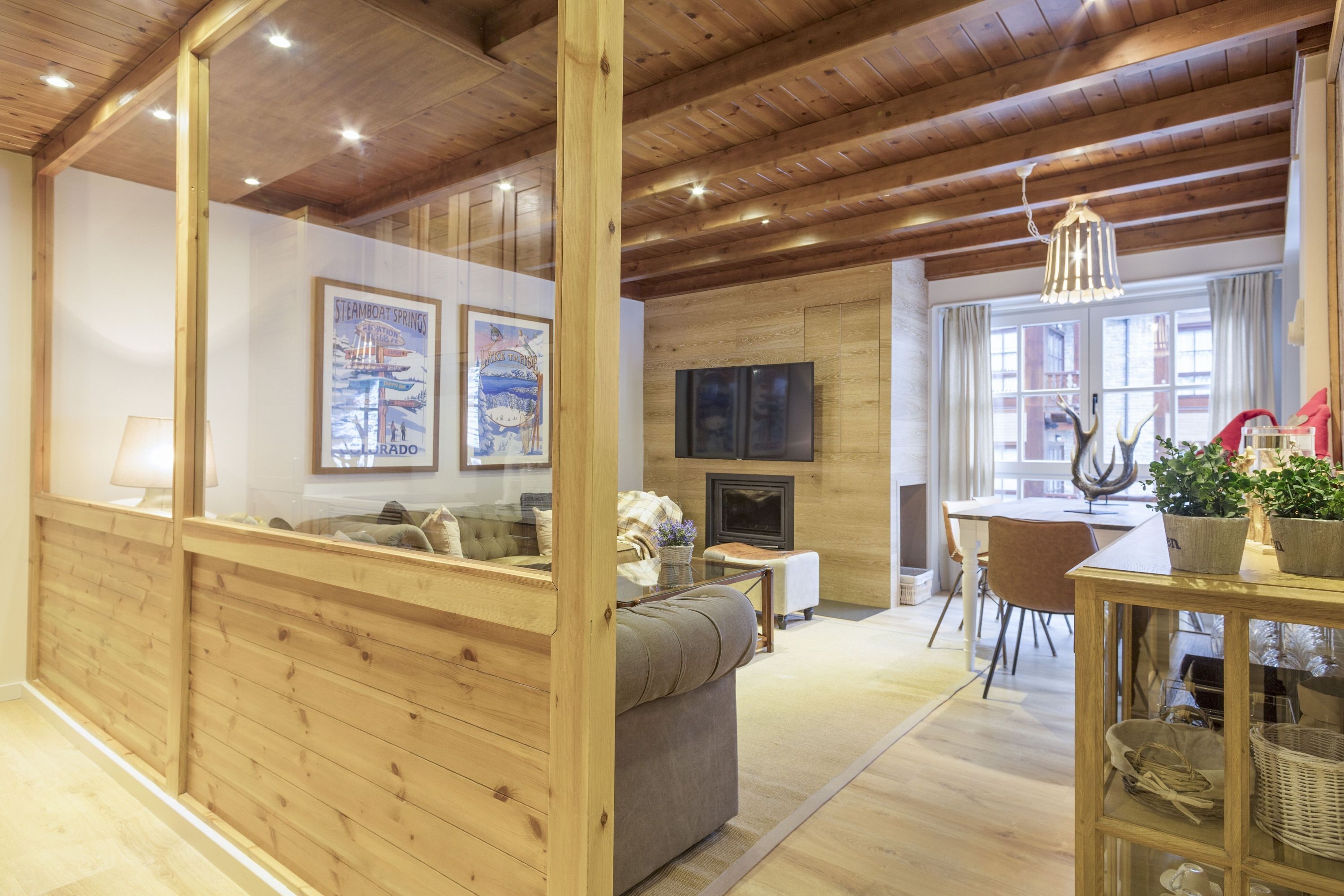 Un accogliente soggiorno con pareti e soffitto in legno, un camino, una televisione e un'area pranzo con tavolo e sedie.