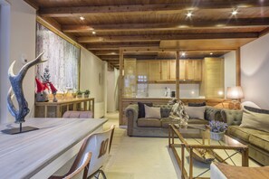A cozy living room with a wooden ceiling, a sofa, a coffee table, and a dining area with a table and chairs. - Luderna - Apartamento Val de Ruda A19 de Saumet (Baqueira)