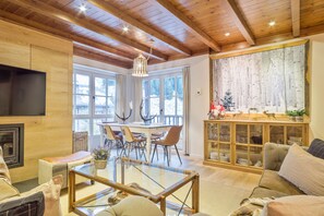 A spacious living area with a glass coffee table, a fireplace, and a dining area with a large window. - Luderna - Apartamento Val de Ruda A19 de Saumet (Baqueira)