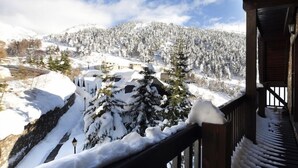 A snow-covered mountain landscape with a wooden building and a balcony.