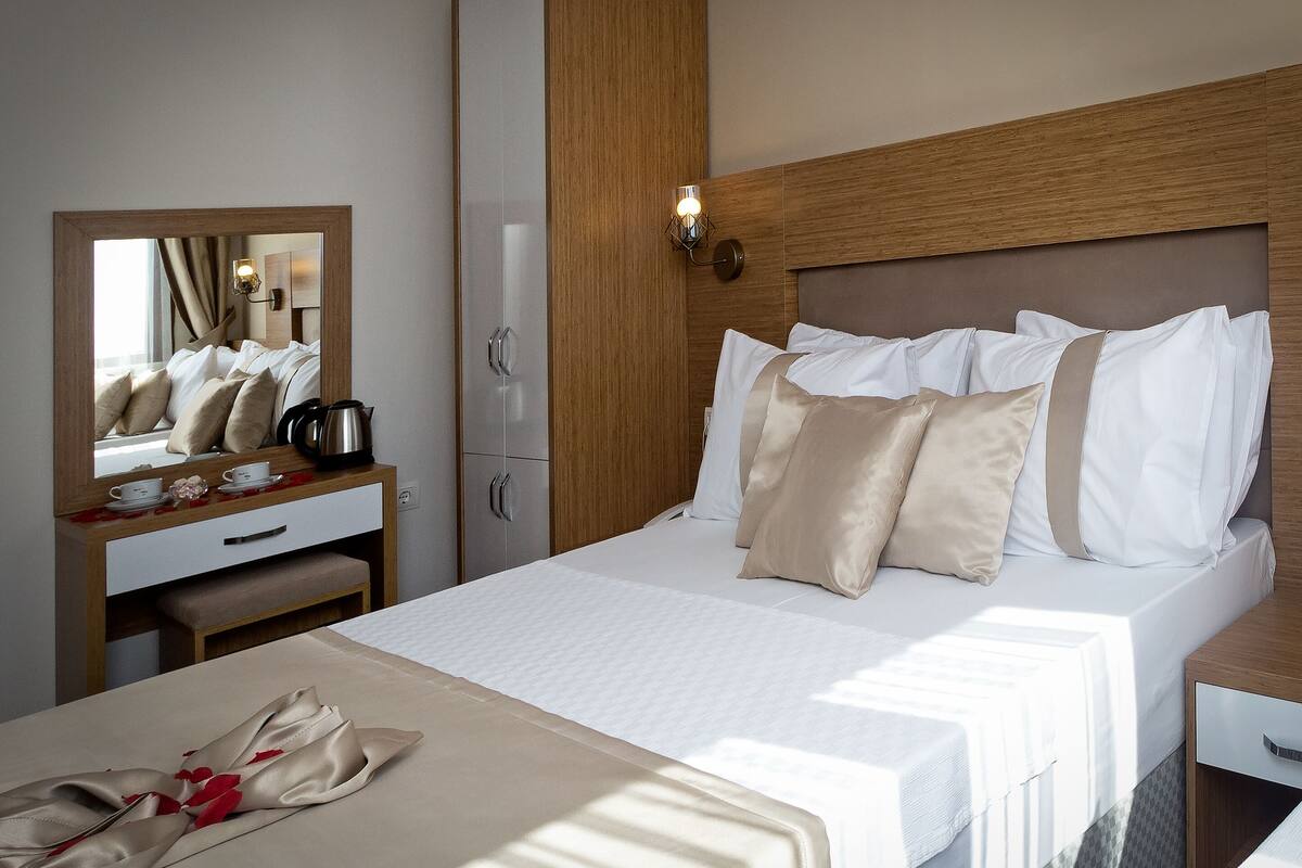 Et hotelværelse med seng, natbord, spejl og skab.
