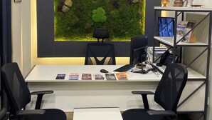 Un bureau moderne  équipé d’un bureau, de deux chaises, d’un tableau blanc et d’une horloge murale indiquant plusieurs fuseaux horaires.