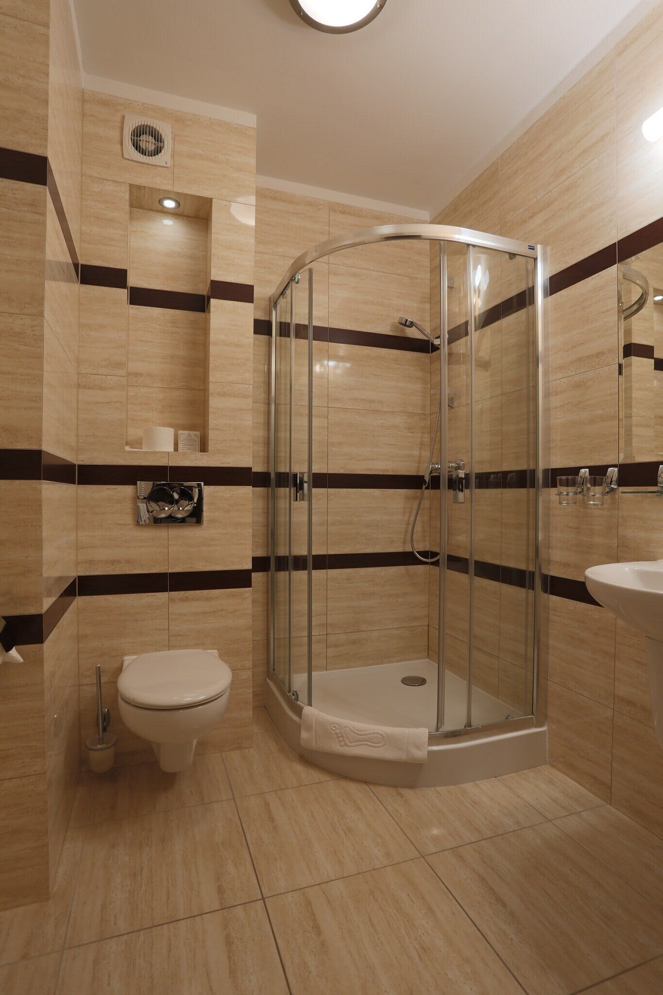 A modern bathroom with a glass-enclosed shower, a toilet, and a sink.