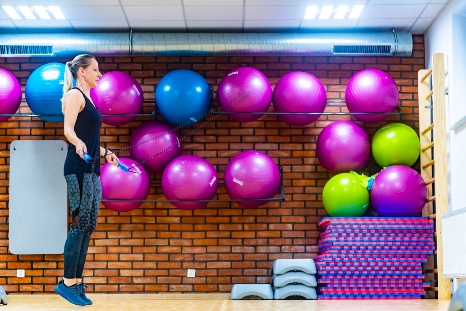 Ein Fitnessraum mit Übungsbällen auf Regalen und einer Tafel an der Wand.