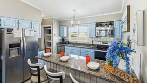A modern kitchen with granite countertops, stainless steel appliances, and blue cabinetry. - Fantastic Ocean Views, Community Pool, Dogs Welcome, Open Deck, KHSDA5 (Kitty Hawk)