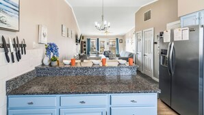 A kitchen with granite countertops, blue cabinets, a stainless steel refrigerator, and a chandelier. - Fantastic Ocean Views, Community Pool, Dogs Welcome, Open Deck, KHSDA5 (Kitty Hawk)