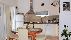 Una cocina compacta con microondas, lavamanos y un reloj en la pared.