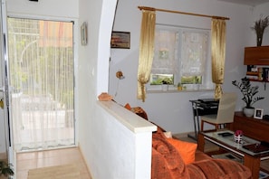 A living room with a sofa, a dining table, and a window with curtains.