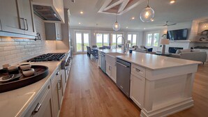 Una cocina amplia con una isla central, un comedor con sillas y un ventanal con vistas.
