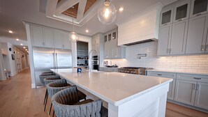 Cocina moderna con una isla grande, alacenas blancas e iluminación colgante.