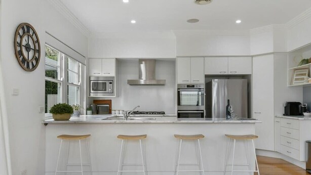 A modern kitchen with white cabinetry, stainless steel appliances, and a central island with bar stools. - Leafy Lamrock • Across from Park • Walk to CBD (Orange)