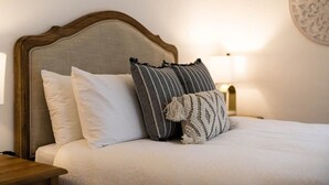 A neatly made bed with a wooden headboard, two white pillows, and a striped pillow with tassels. - Leafy Lamrock • Across from Park • Walk to CBD (Orange)