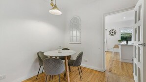 A dining area with a round table, four chairs, a pendant light, and a decorative window. - Leafy Lamrock • Across from Park • Walk to CBD (Orange)