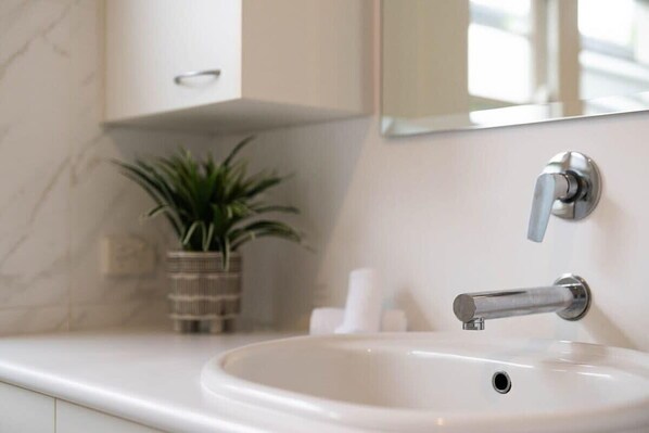 A bathroom with a white sink, a mirror, and a potted plant. - Leafy Lamrock • Across from Park • Walk to CBD (Orange)