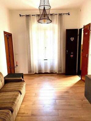 Ein Zimmer mit Holzboden, einer Couch, einer Tür mit Herz-Dekoration und einer Pendelleuchte.