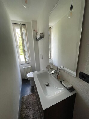 Ein modernes Badezimmer mit einem weißen Waschbecken, einem Spiegel und einem Fenster.