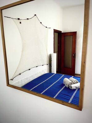 Una habitación con cama, puerta y un espejo montado en la pared.