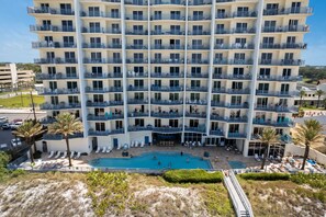 Un hôtel à plusieurs étages doté de balcons, d’une piscine et d’un espace de plage.