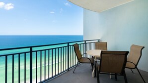 Een balkon met uitzicht op de oceaan, een ronde tafel en twee stoelen.