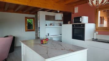 Une cuisine compacte avec des meubles blancs, un plan de travail en marbre, un four encastré et un four à micro-ondes.