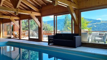Un intérieur en bois avec une piscine, de grandes fenêtres et un espace salon extérieur.