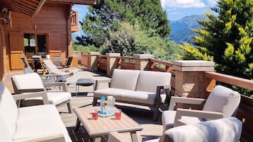 Une terrasse en bois aménagée avec du mobilier d’extérieur, notamment des canapés et des fauteuils, ainsi qu’une table avec des boissons.