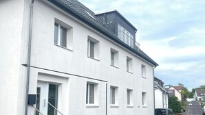 A white two-story residential building with a balcony on the upper floor. - Apartment Schloofschdubb in Fuldatal bei Kassel (Fuldatal)