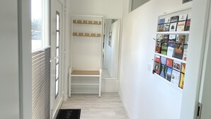 A hallway with a coat rack, a bench, and a wall with informational posters. - Apartment Schloofschdubb in Fuldatal bei Kassel (Fuldatal)