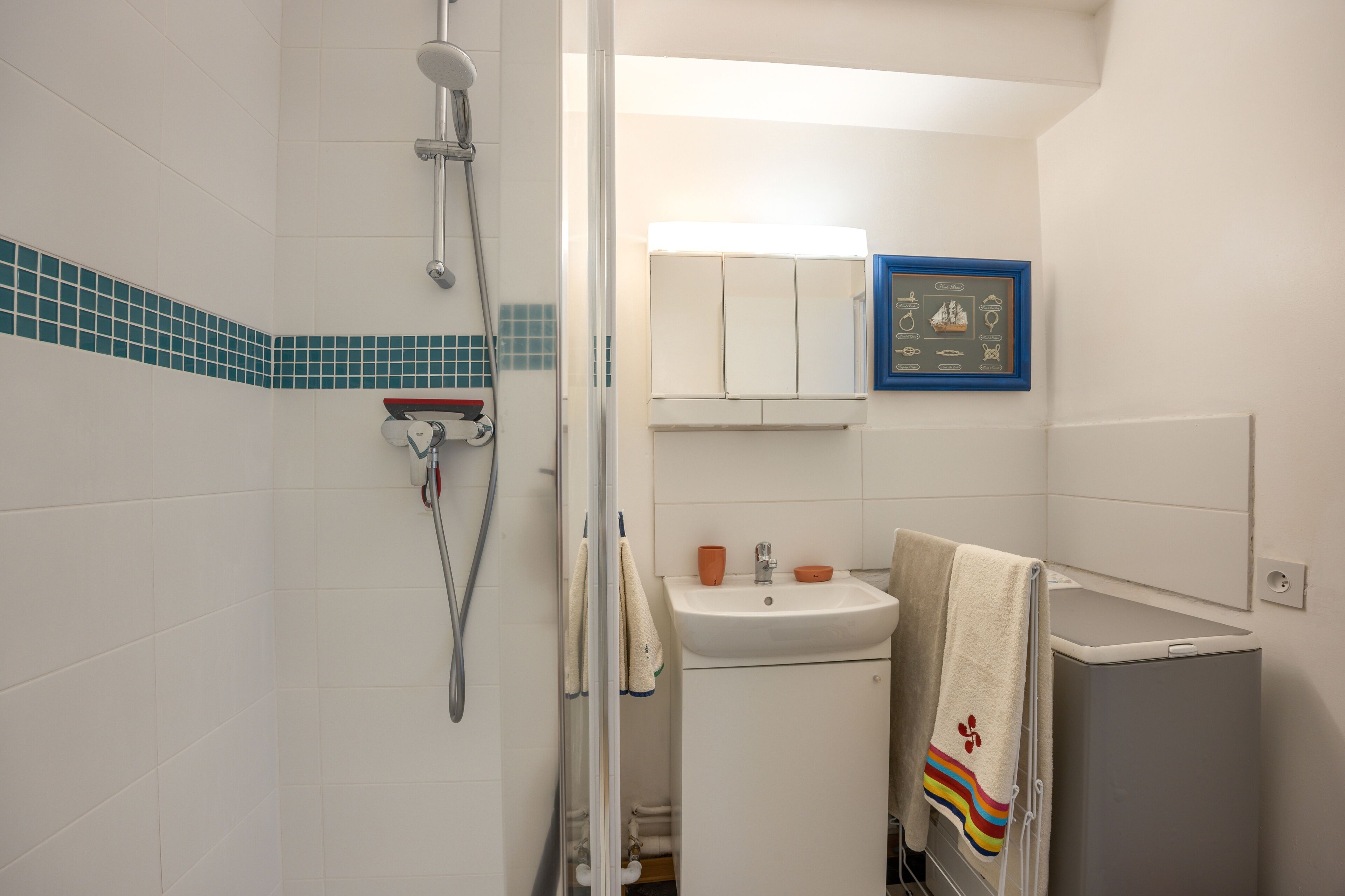 Un bagno con doccia, lavandino e un quadro appeso al muro.