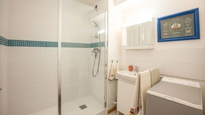 A bathroom with a glass-enclosed shower, a sink with a towel, and a framed picture on the wall. - Sunan - Appartement avec balcon (Courseulles-sur-Mer)