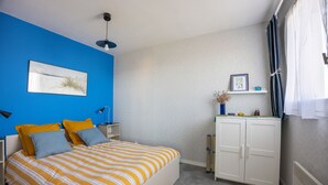 A bedroom with a bed, a nightstand, a desk, and a wardrobe. - Sunan - Appartement avec balcon (Courseulles-sur-Mer)