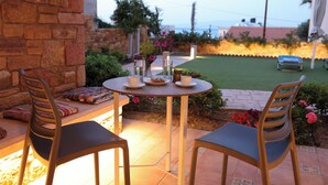 Een terras buiten met twee stoelen, een tafel en kaarsen.