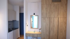 Een kleine keuken met een spoelbak, een klein krukje en houten kastjes.