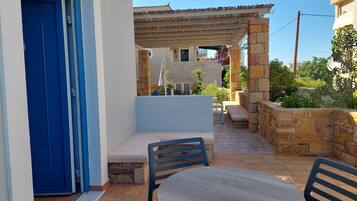 A patio with a round table and chairs, a blue door, and a stone wall.