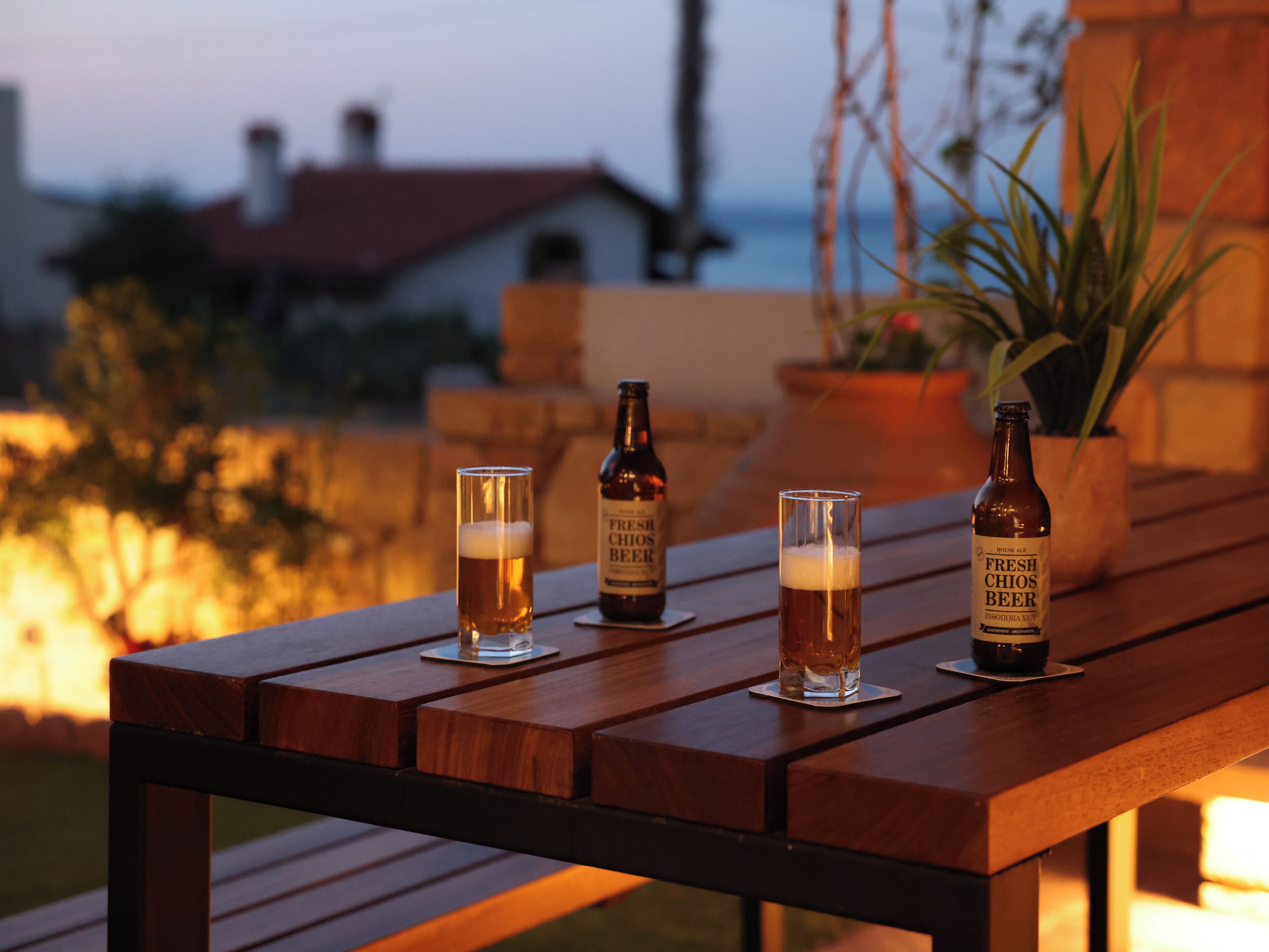 Ein Holztisch mit zwei Gläsern und zwei Bierflaschen.