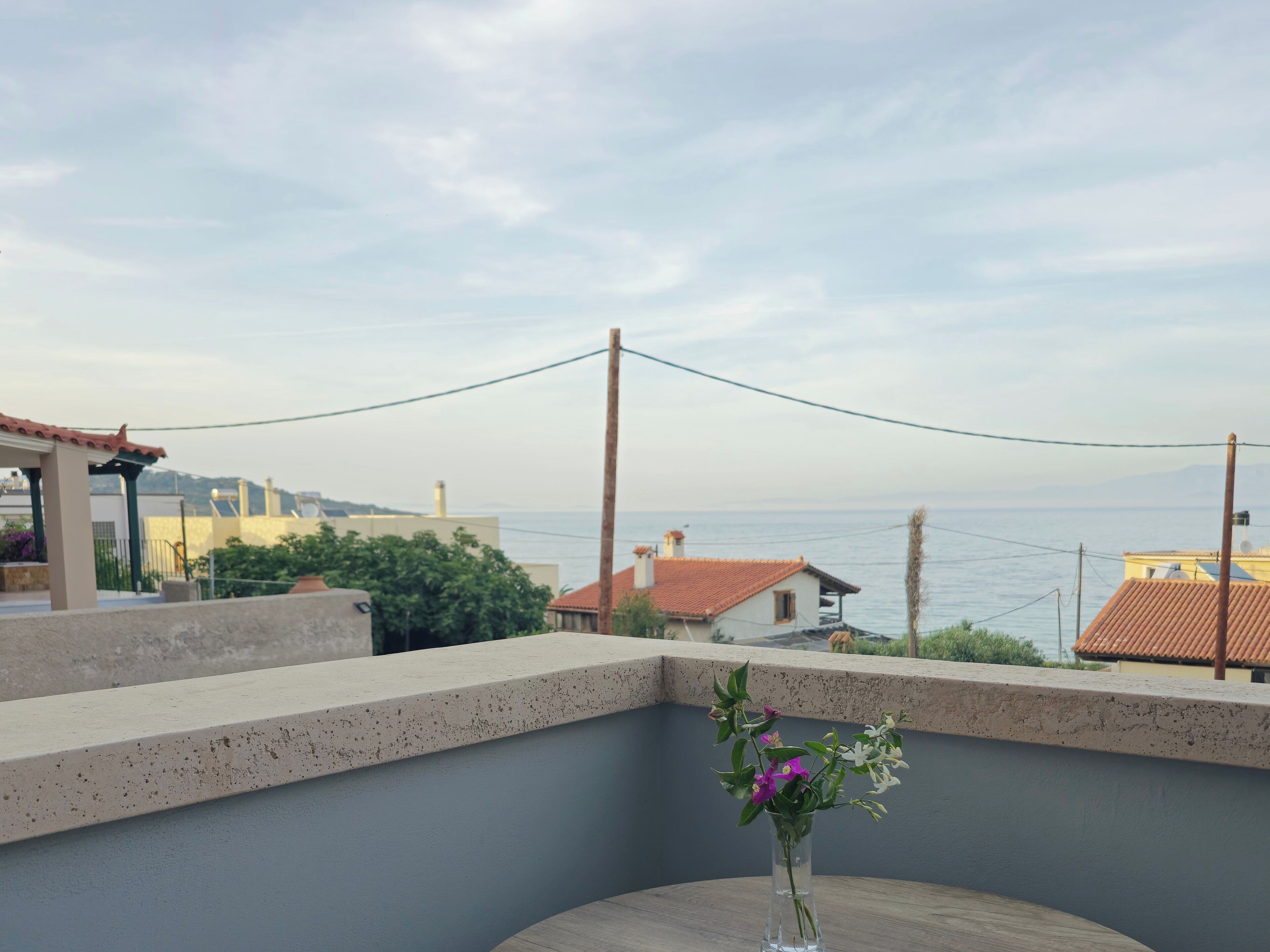 A balcony with a clear view of the sea and buildings in the background.