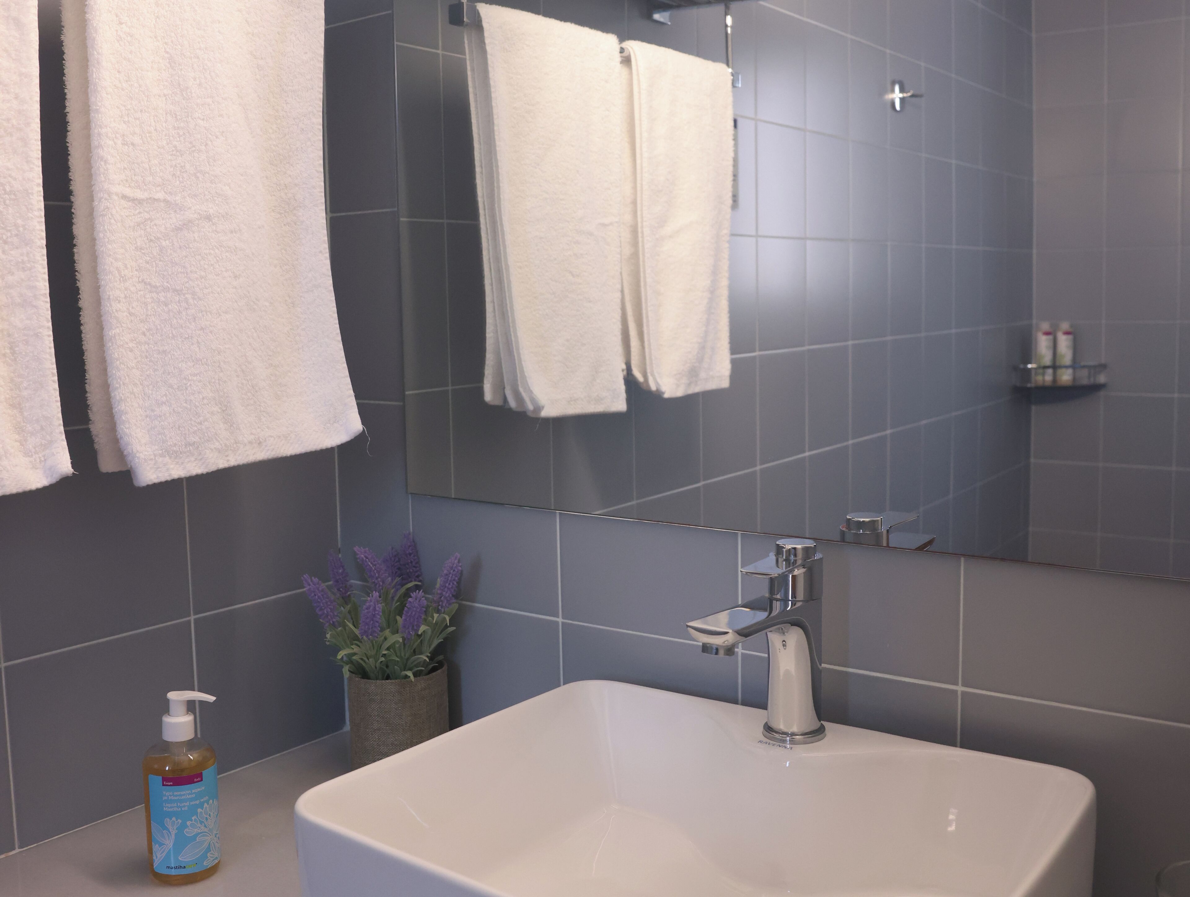 A bathroom with a white sink, a mirror, and two towels hanging on the wall.