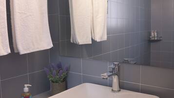 A bathroom with a white sink, a mirror, and two towels hanging on the wall.