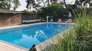 Ein rechteckiger Pool mit Holzterrasse und überdachtem Bereich.