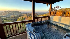 Un bain à remous sur une terrasse en bois, avec vue sur un paysage boisé.