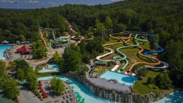 Vue aérienne d’un parc aquatique doté de nombreux toboggans et de plusieurs piscines, le tout entouré d’une végétation luxuriante.