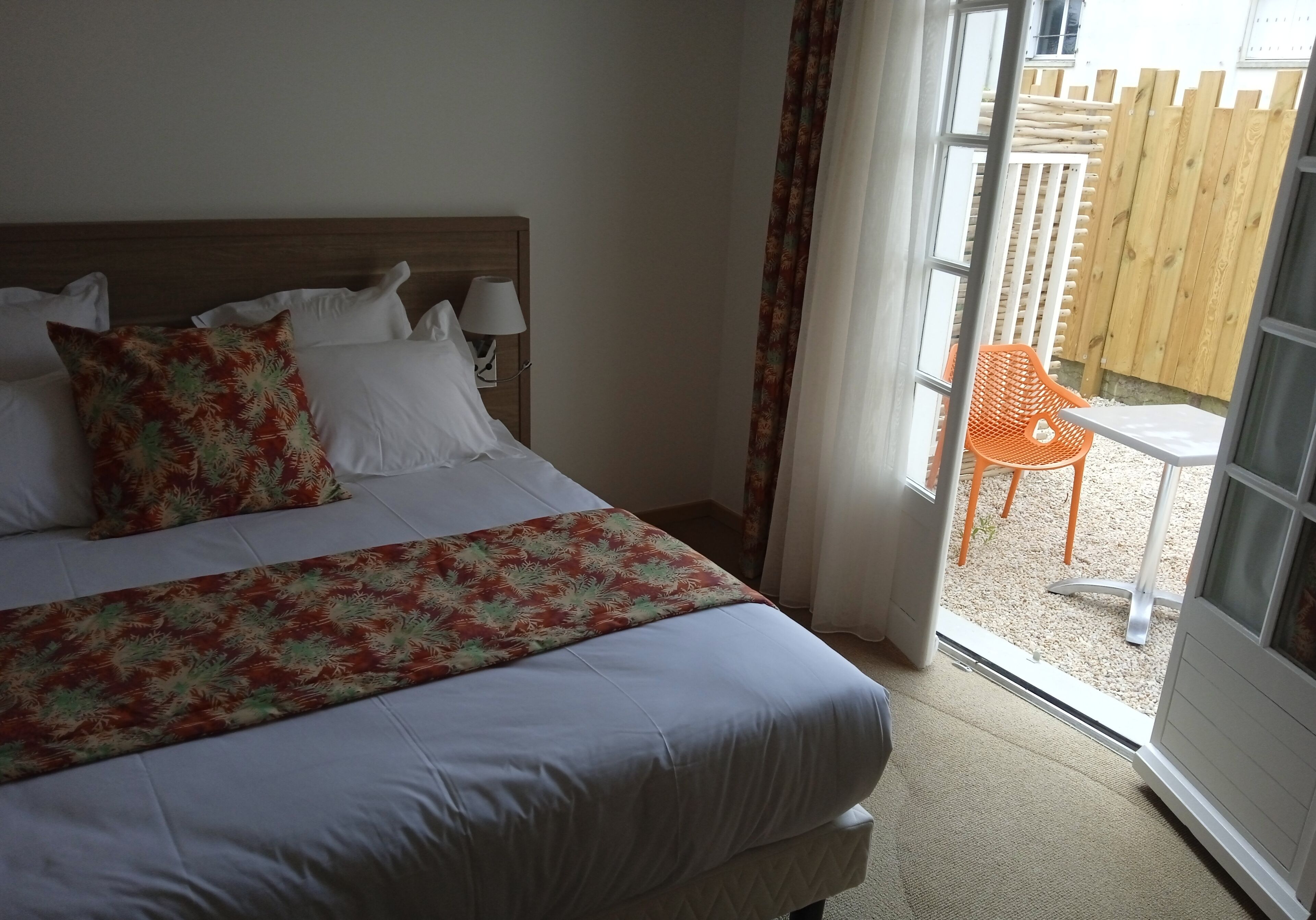 A bedroom with a bed, pillows, a nightstand, and a window with curtains.