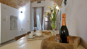 A dining table with a bottle of champagne, a vase with flowers, and a box of pastries. - La Vigna Salentina - Garden and Private Pool (Alessano)