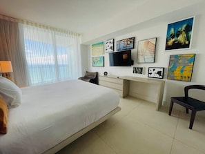 Une chambre d’hôtel avec un grand lit, un bureau et plusieurs œuvres d’art encadrées accrochées au mur.