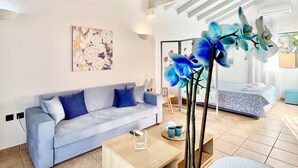 En moderne stue med en blå sofa, et sofabord og et stort vindue med blå orkidéer.