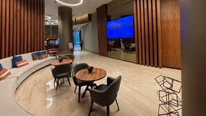Een modern interieur met een gebogen zithoek, ronde tafels en een grote flatscreen-televisie.