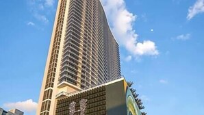 Een modern hoog hotel met een opvallende, gebogen gevel en een grote muurschildering op de begane grond.