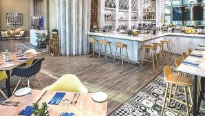 A modern bar area with a bar counter, stools, and a variety of bottles and glasses.