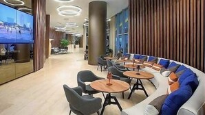 A modern lounge area with a curved sofa, round tables, and a flat-screen TV.