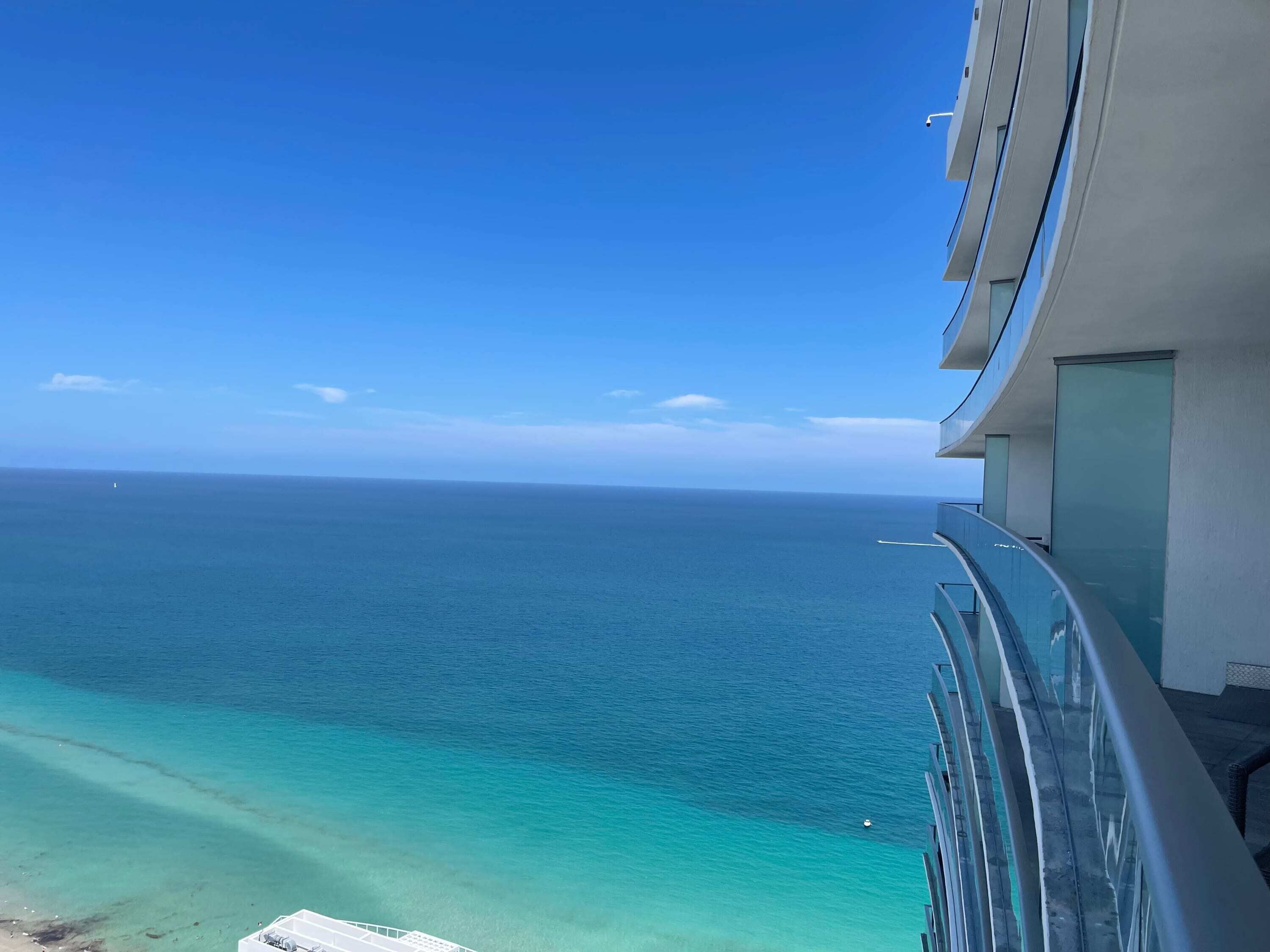 A balcony with a view of the ocean and a modern building.